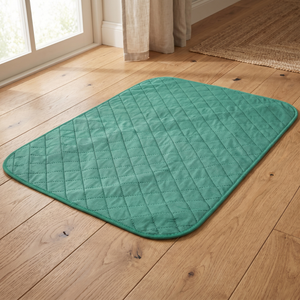 Teal quilted pet cooling mat on hardwood floor near window for cats and dogs comfort
