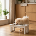 Fluffy Pomeranian eating from elevated white pet feeder with stainless steel bowls in cozy kitchen
