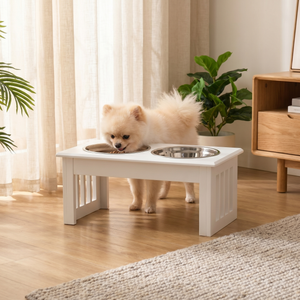 Small dog eating from elevated white pet feeder with two stainless steel bowls in cozy home setting