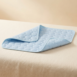 Light blue quilted pet cooling mat for cats and dogs, soft comfort design on beige surface
