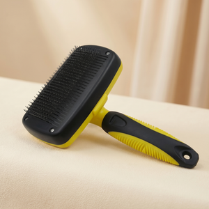 Yellow and black pet grooming brush for cats and dogs with ergonomic handle on soft surface