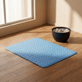 Blue quilted cooling mat for cats and dogs beside a pet water fountain on hardwood floor near window